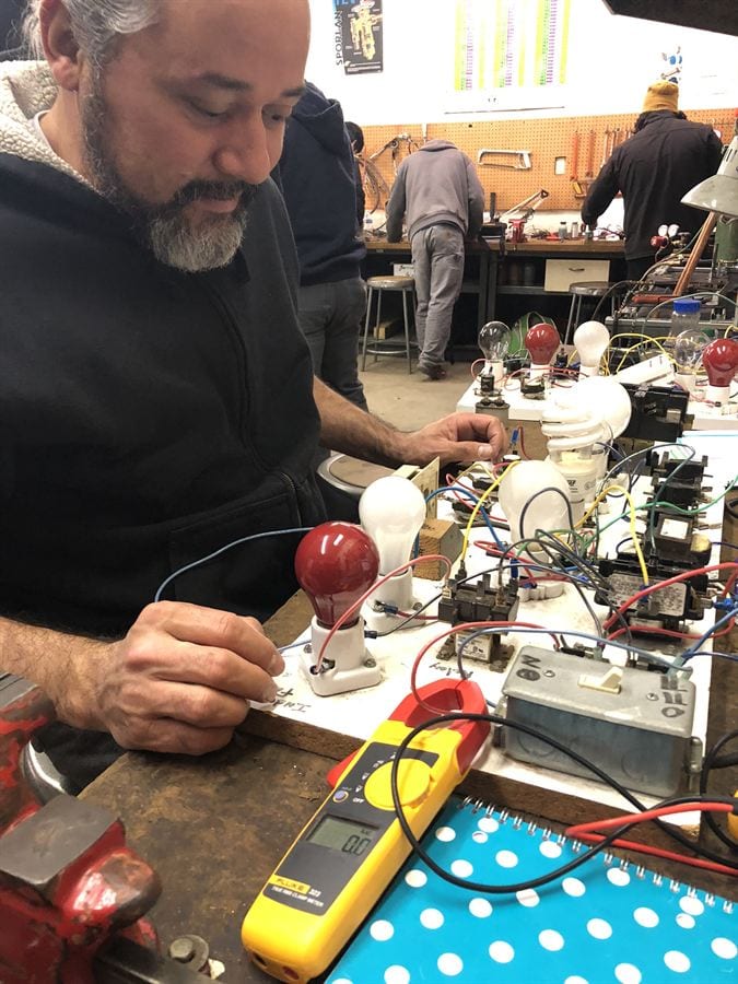 Close-up of a student using a Fluke multimeter to take voltage readings