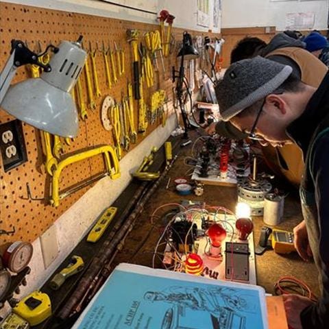 Students at training benches working hands-on with HVAC components