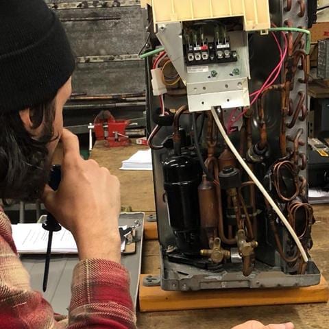 Student running a diagnostic check on HVAC training equipment