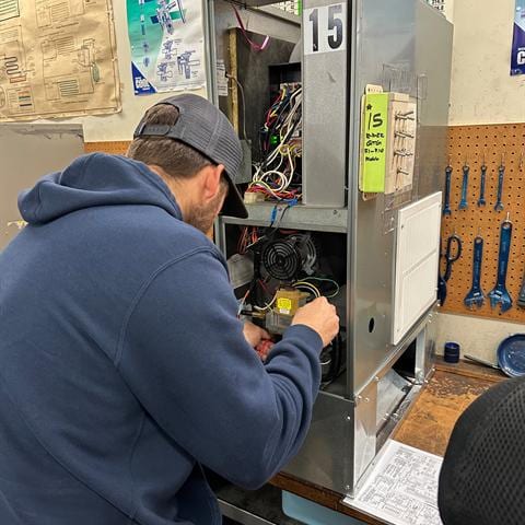 Student at an HVAC training station working on real equipment