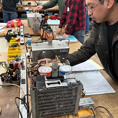 Student studying an HVAC component up close